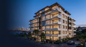 Modern glass-fronted apartment building at dusk with illuminated balconies and a waterfront city skyline in the background, labeled 'The Pinnacle'